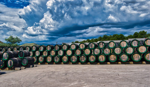 Stack of wine barrels on field against sky