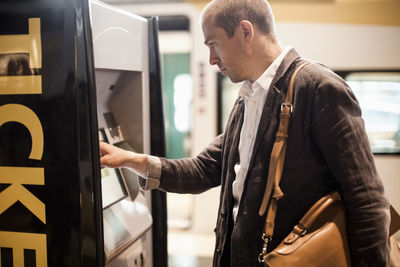 Businessman using ticket machine at railway station