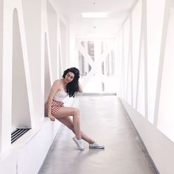 Full length of woman sitting at corridor