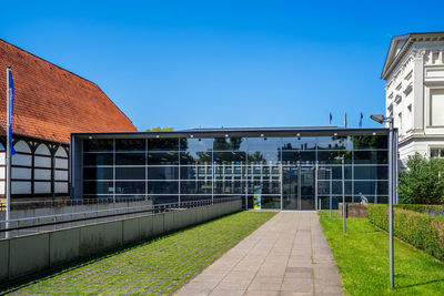 Footpath amidst buildings against clear blue sky