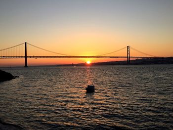 April 25th bridge over tagus river against sky during sunset