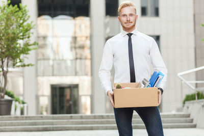 Man holding camera while standing in front of building