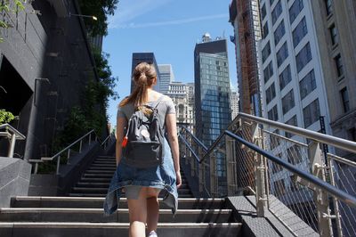 Rear view of woman moving on steps in city