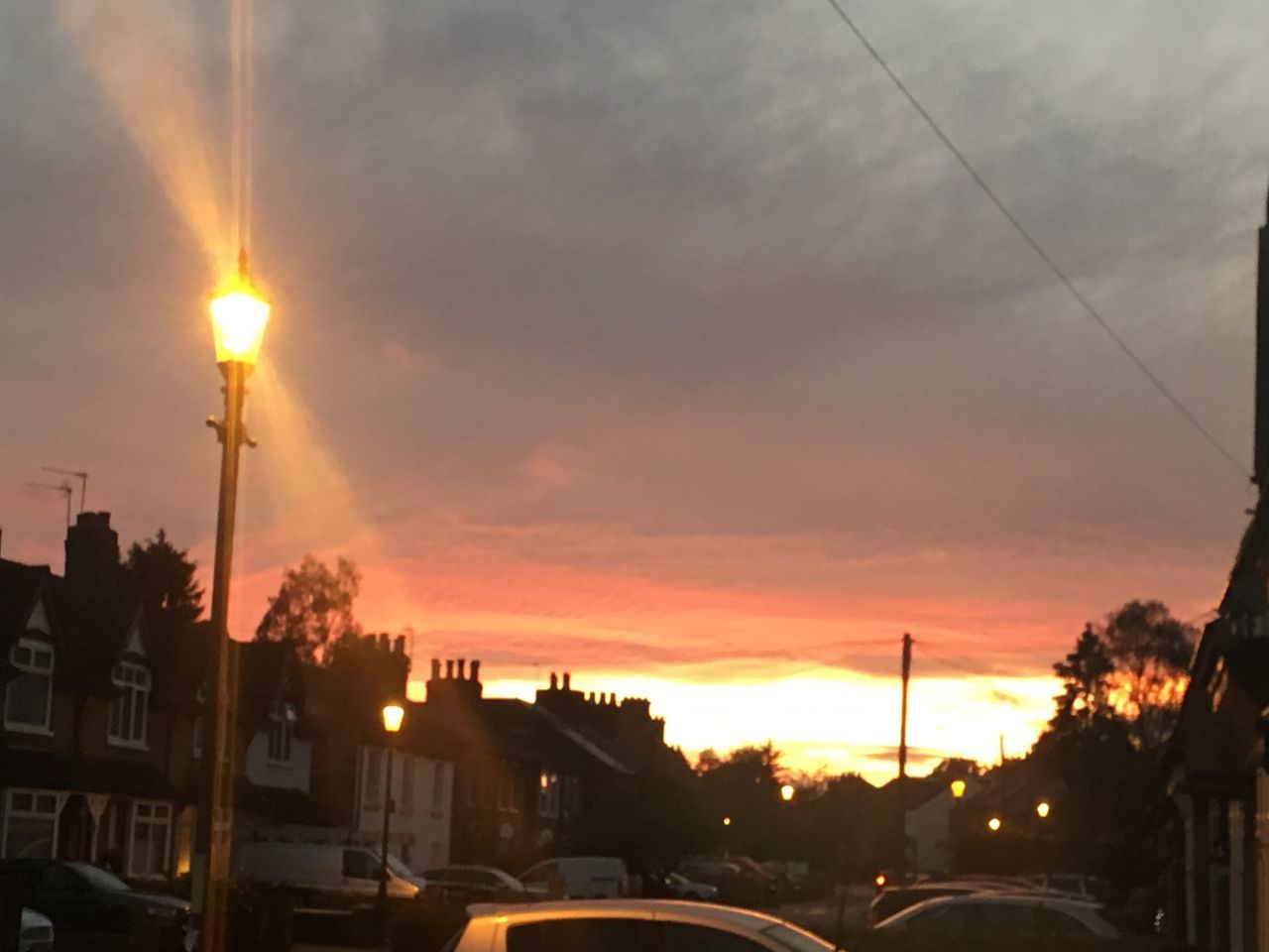 SILHOUETTE STREET BY BUILDINGS AGAINST SKY DURING SUNSET