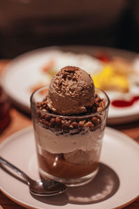 Delicious sweet chocolate ice cream in a transparent glass with chocolate chips and caramel cream