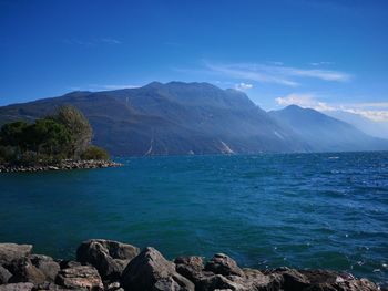 Scenic view of sea and mountains against blue sky