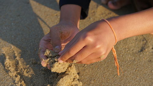 Close-up of hands on sand