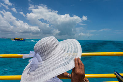 Close-up of hand against sea against sky