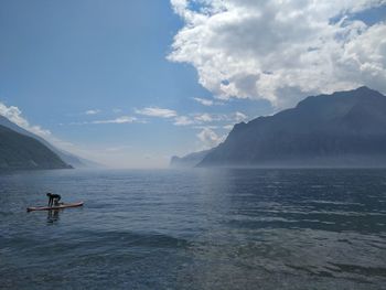 Man on paddleboard in river against sky