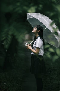 Woman holding umbrella standing during rainy season