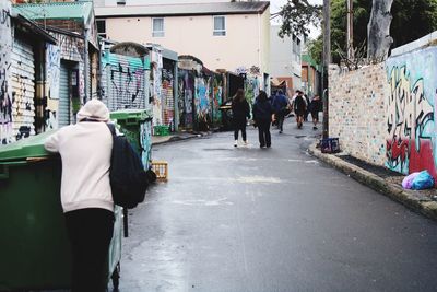 Rear view of people walking on road in city