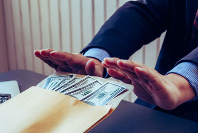 Close-up of hand holding paper with tattoo on table