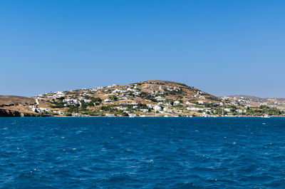 Sea by mountain against clear blue sky