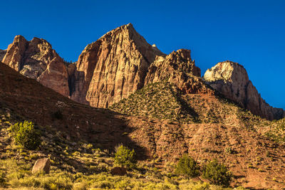 Low angle view of rocky mountain against blue sky