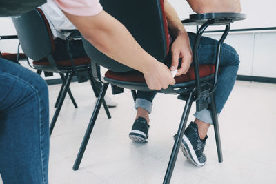 Low section of people sitting on chair