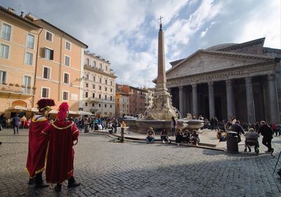 People at town square against cloudy sky