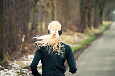 Rear view of woman walking on road in forest