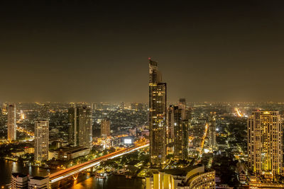 Illuminated buildings in city against sky at night