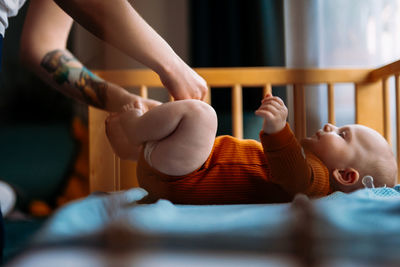 Mother changing diaper of son at home