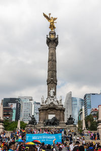 Statue in city against cloudy sky