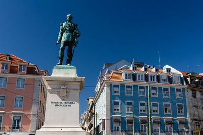 Low angle view of statue against buildings in city