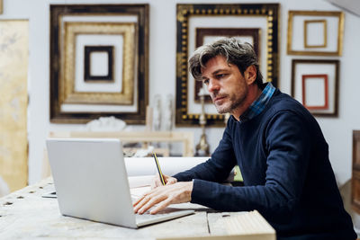 Mature man using laptop working in workshop