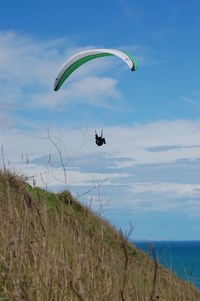 Low angle view of person paragliding over sea against sky