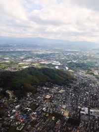 Aerial view of cityscape against cloudy sky