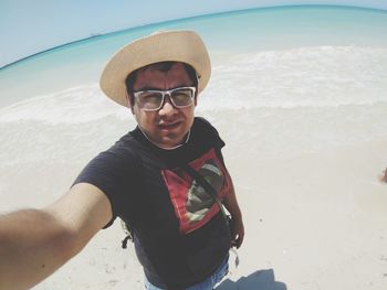 Portrait of man wearing hat standing at beach