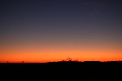 Silhouette landscape against clear sky at sunset
