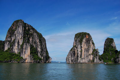 Panoramic view of rock formations in sea against blue sky