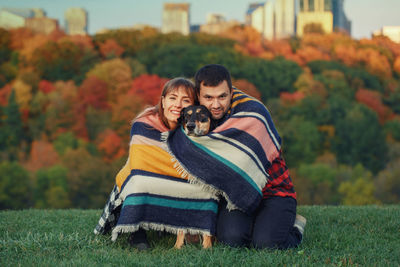 Portrait of couple with dog siting in park during autumn