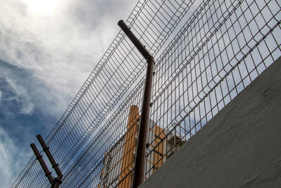 Low angle view of barbed wire fence against sky