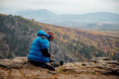 Man sitting on rock looking at mountains