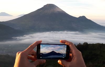 Midsection of man using mobile phone against sky