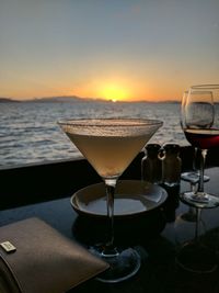 Close-up of martini drink on table against sea during sunset