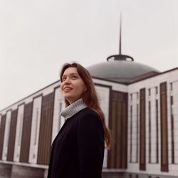 A woman stands near a beautiful building