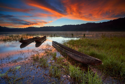 Colorful of sunrise time with traditional boats on the lake tamblingan in bali, indonesia.