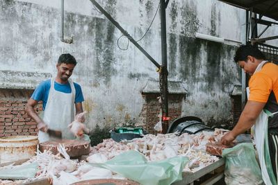 Butchers cutting meat at market stall