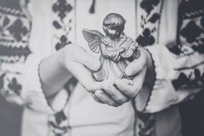 Midsection of woman holding angel sculpture