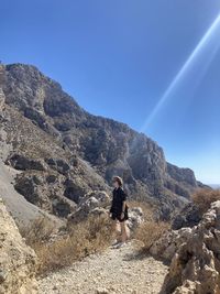 Rear view of man on rock against sky