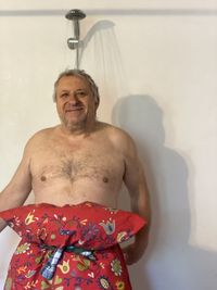 Portrait of shirtless man standing against wall at home