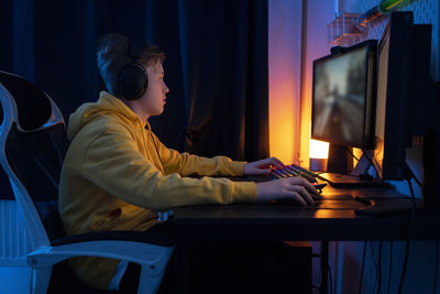 Boy playing game on desktop pc on table at home