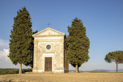 Trees by historic building against clear sky