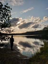 Rear view of man standing by lake against sky
