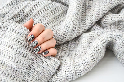 Hand in sweater with zebra animal printed nails. female manicure. glamorous beautiful manicure.