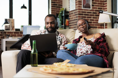 Friends using laptop while sitting on table