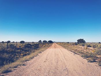 Dirt road against clear blue sky