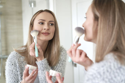 Portrait of young woman applying make-up at home