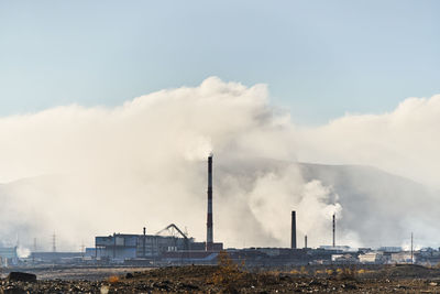 Smoke emitting from factory against sky